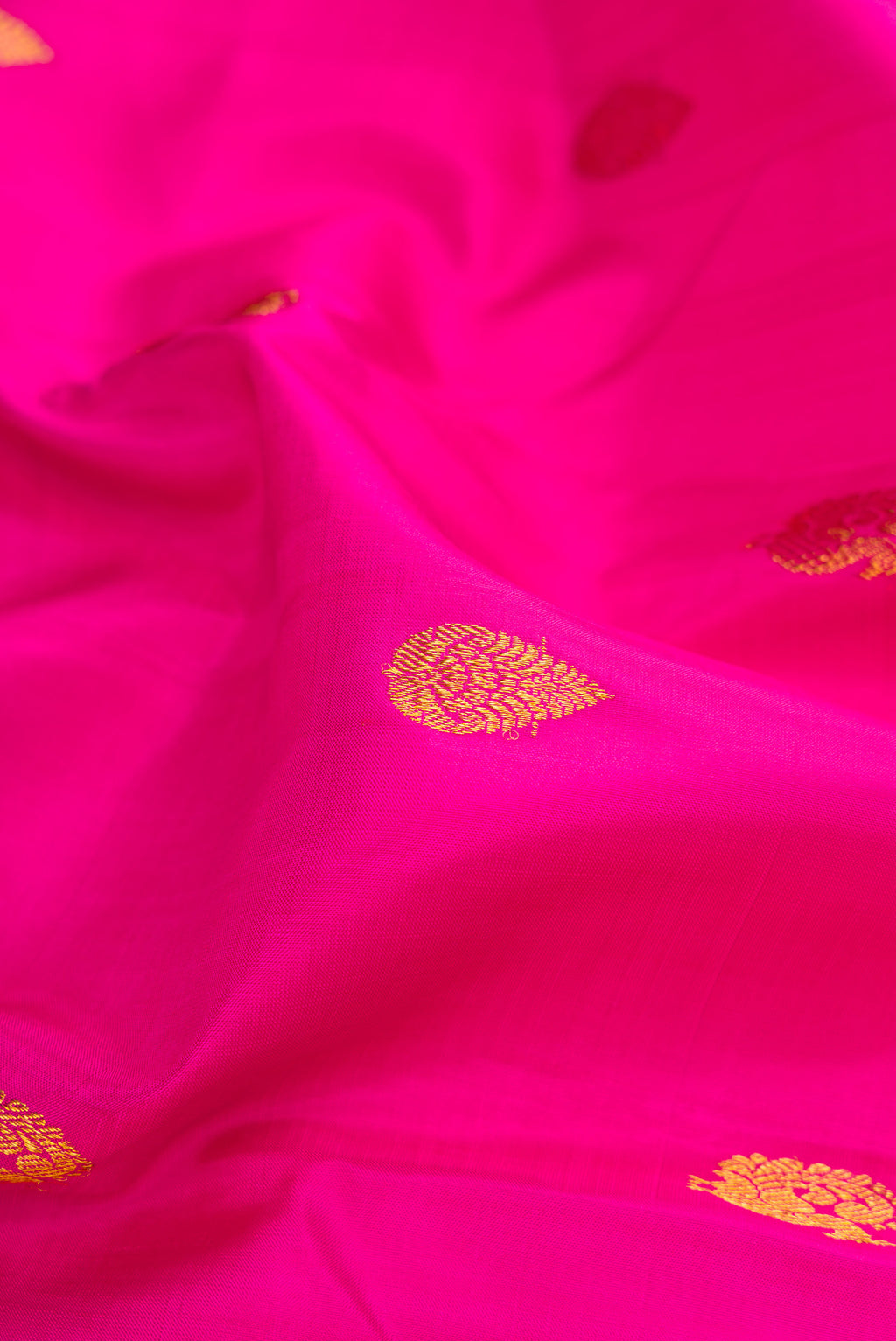 Close up of Pink Kanchipuram Silk Saree with Zari Butta on the body and Zari Border.  displaying folds