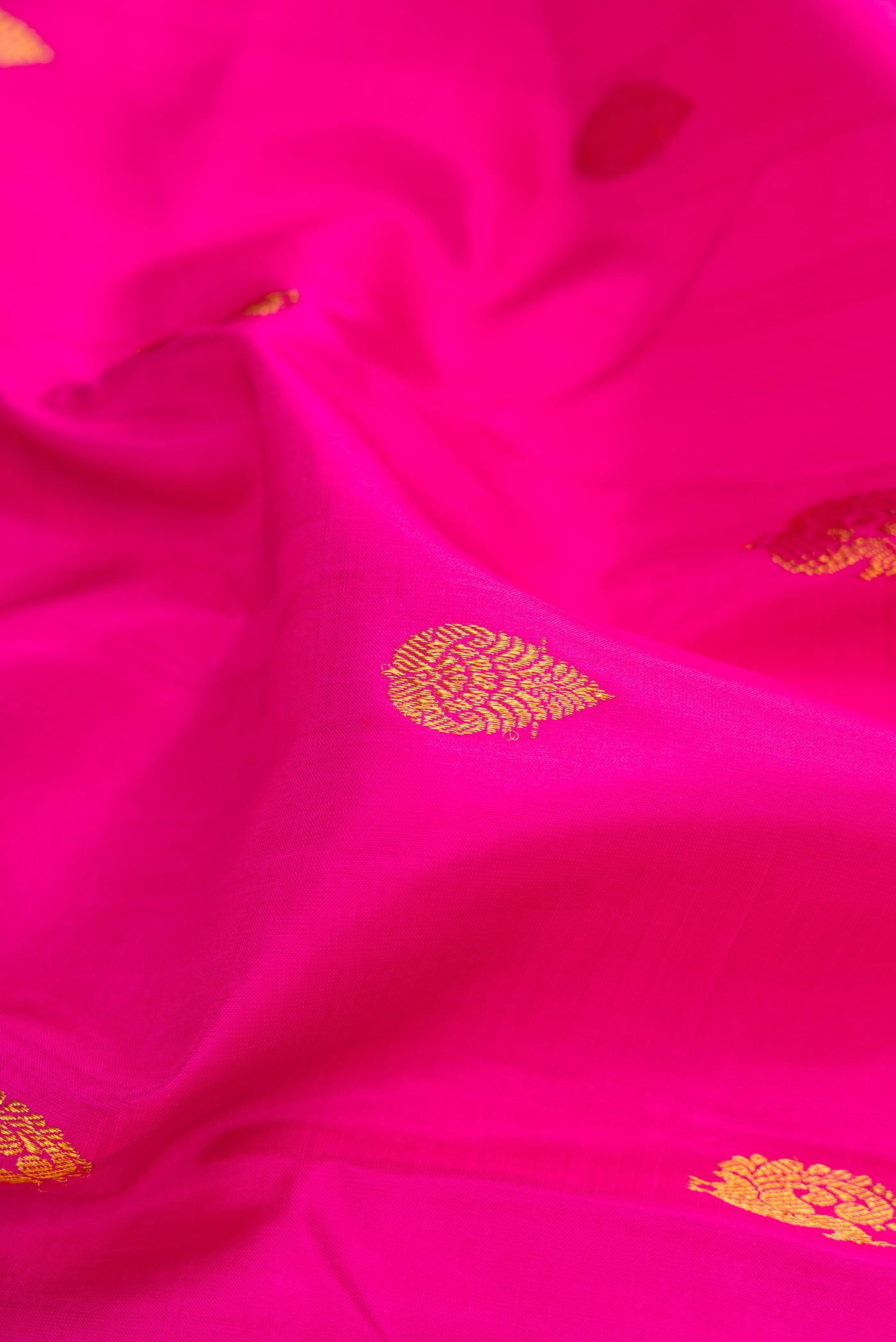 Close up of Pink Kanchipuram Silk Saree with Zari Butta on the body and Zari Border.  displaying folds