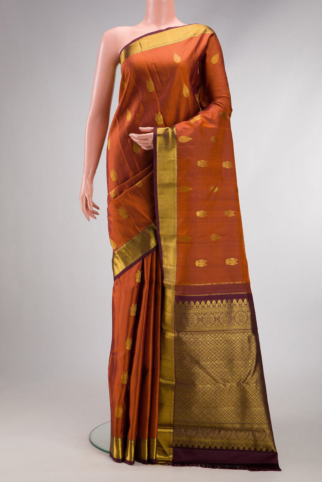 Brick Orange Dual Tone Kanjivaram Silk Saree with Zari Butta on the body and Zari Border.  displayed on a mannequin