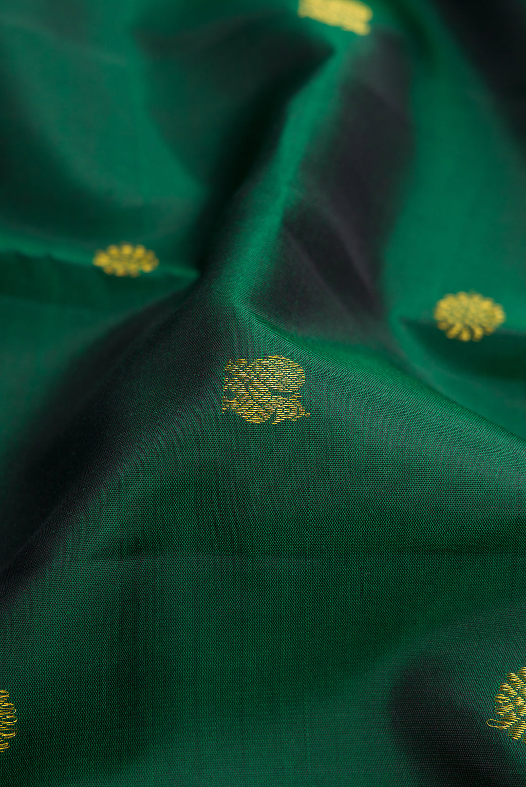 Close up of Bottle Green Kanjivaram Silk Saree with Zari Butta on the body and Zari Border.  displaying folds