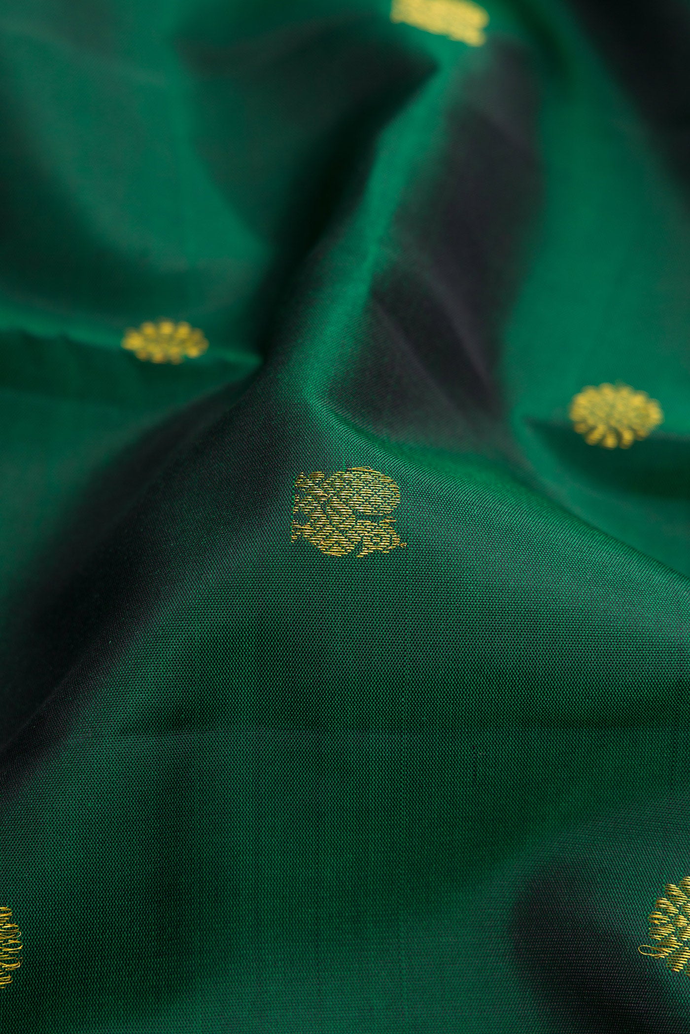 Close up of Bottle Green Kanjivaram Silk Saree with Zari Butta on the body and Zari Border.  displaying folds