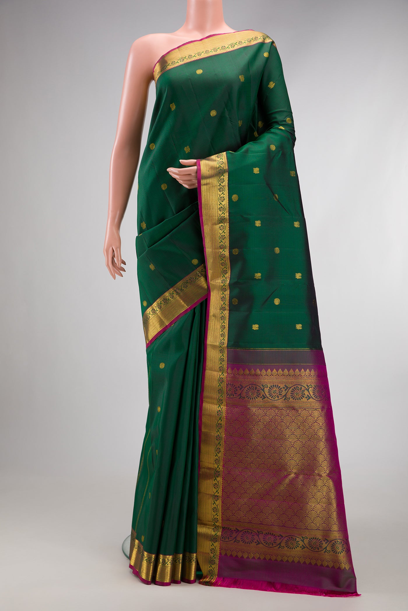Bottle Green Kanjivaram Silk Saree with Zari Butta on the body and Zari Border.  displayed on a mannequin