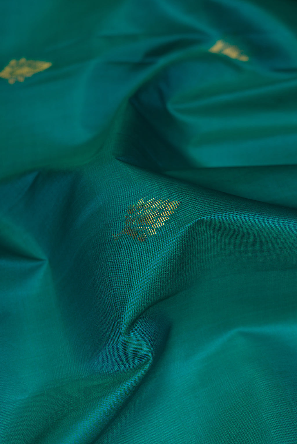 Close up of Teal Soft Silk Saree with Zari Butta on the body and Fancy Border.  displaying folds