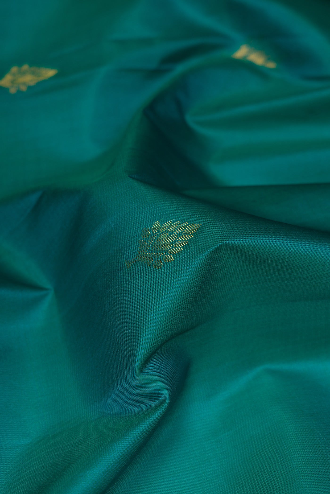 Close up of Teal Soft Silk Saree with Zari Butta on the body and Fancy Border.  displaying folds