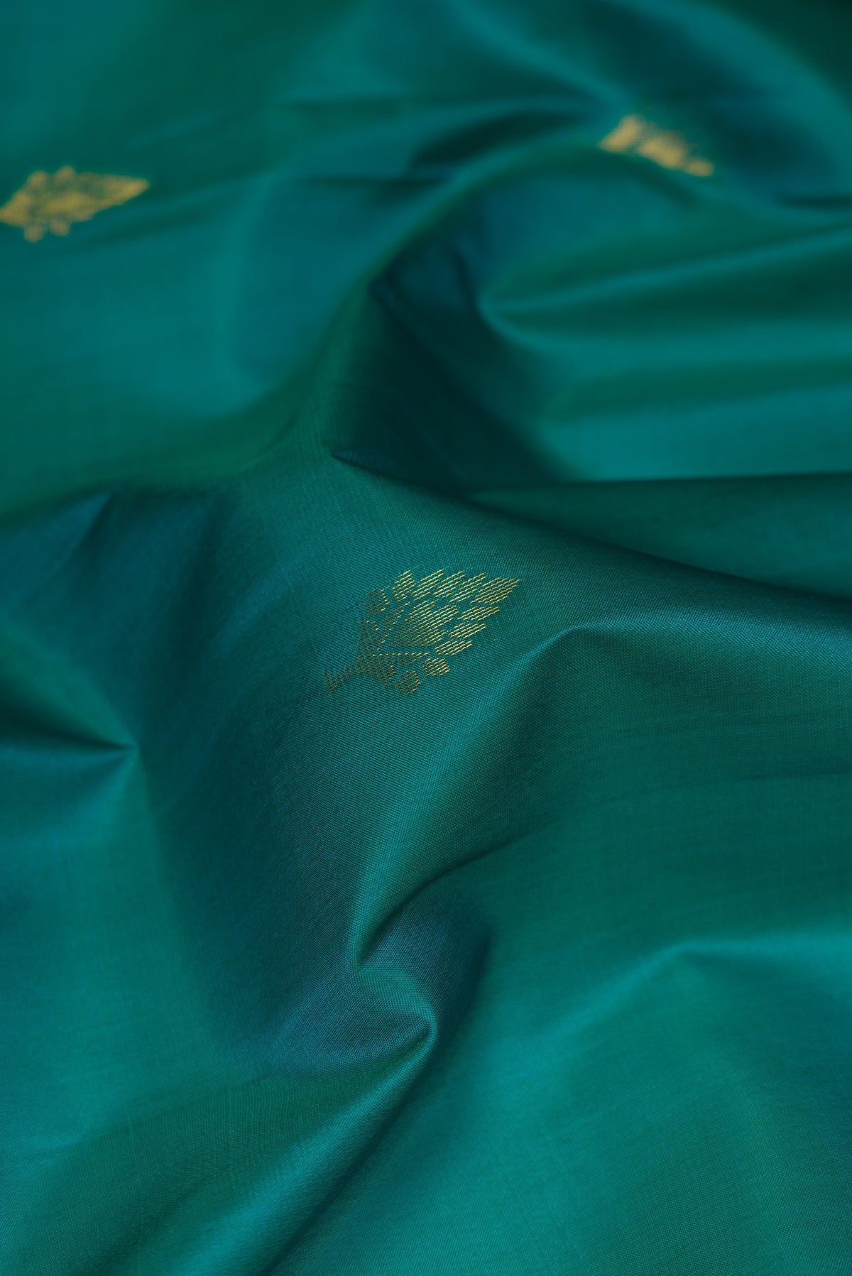 Close up of Teal Soft Silk Saree with Zari Butta on the body and Fancy Border.  displaying folds