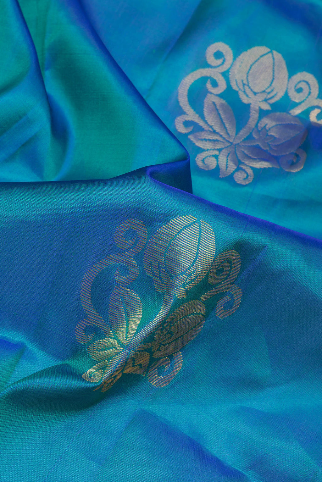 Close up of Peacock Blue Soft Silk Saree with Zari Butta on the body and Zari Border.  displaying folds