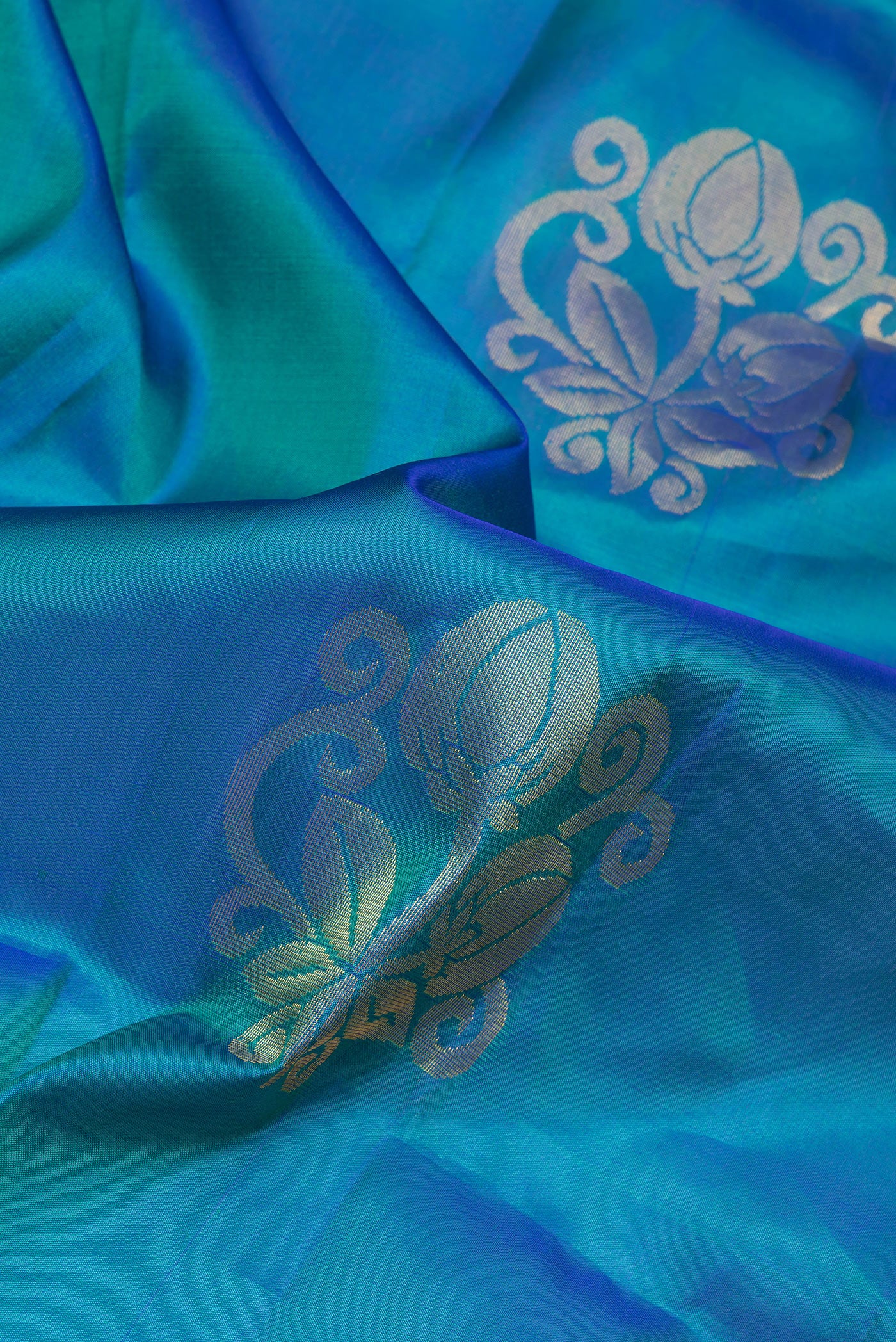 Close up of Peacock Blue Soft Silk Saree with Zari Butta on the body and Zari Border.  displaying folds