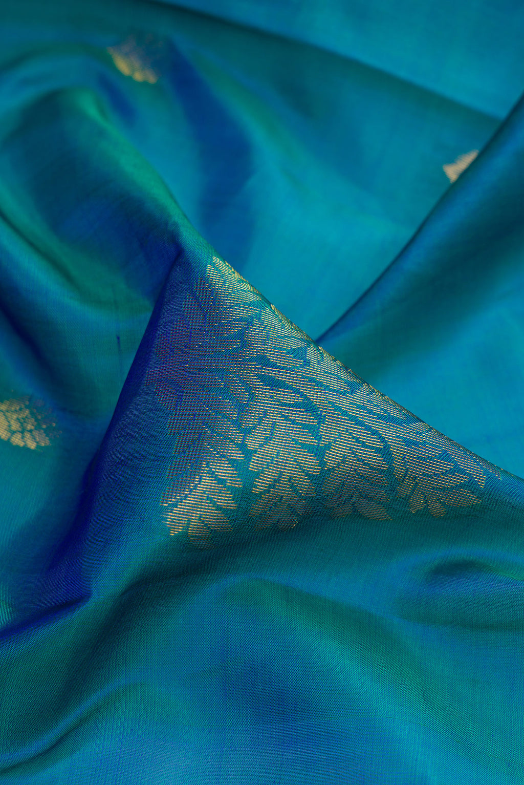 Close up of Peacock Blue Dual Tone Soft Silk Saree with Zari Butta on the body and Fancy Border.  displaying folds