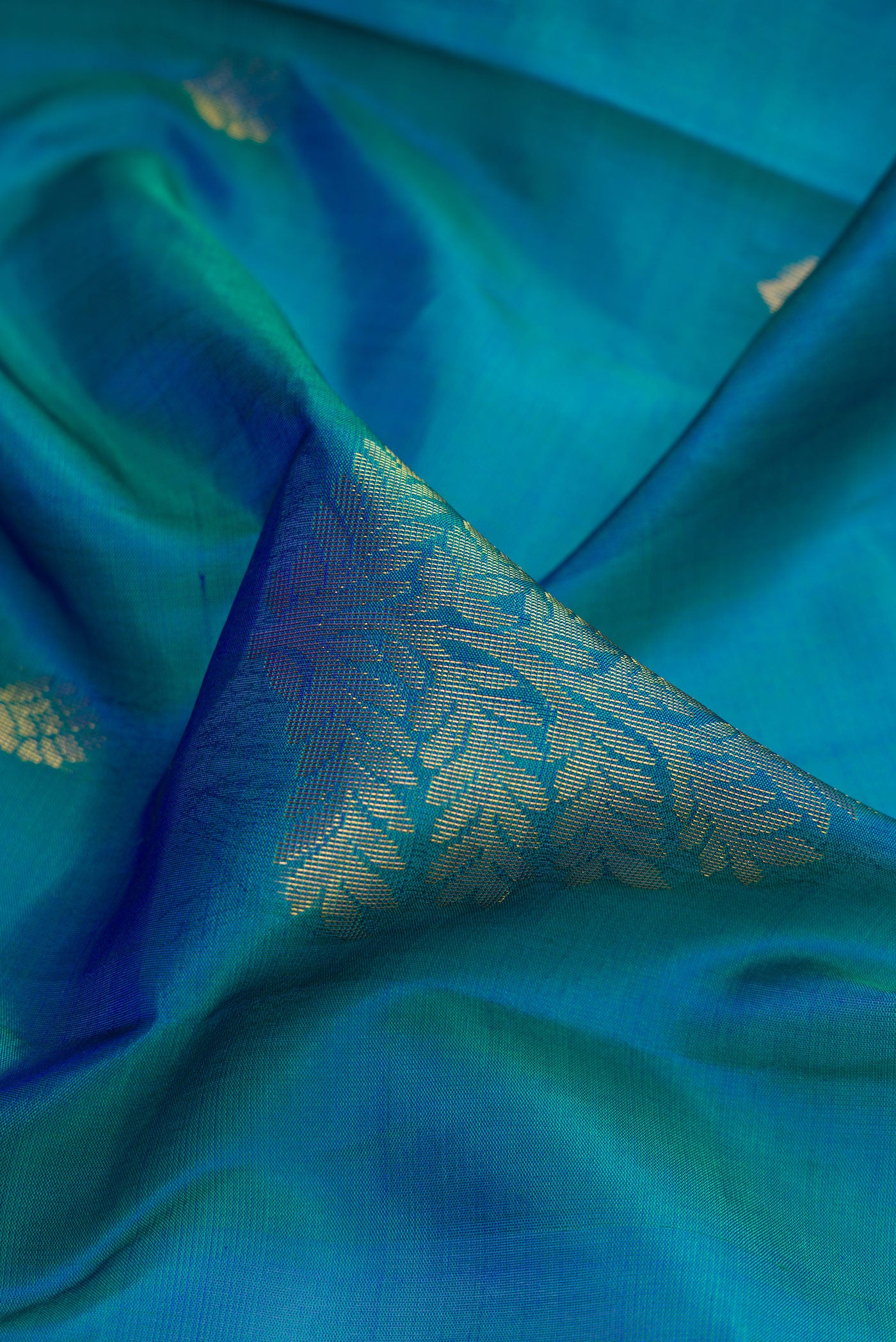 Close up of Peacock Blue Dual Tone Soft Silk Saree with Zari Butta on the body and Fancy Border.  displaying folds
