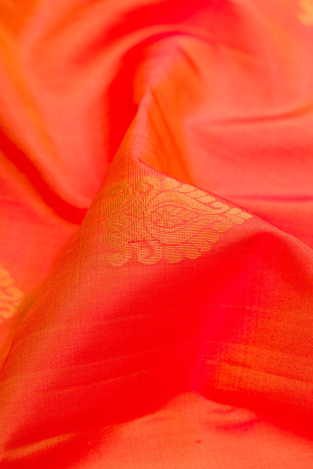 Close up of Orange Dual Tone Soft Silk Saree with Zari Butta on the body and Fancy Border.  displaying folds