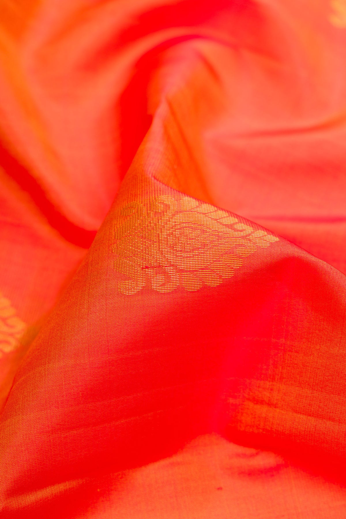 Close up of Orange Dual Tone Soft Silk Saree with Zari Butta on the body and Fancy Border.  displaying folds