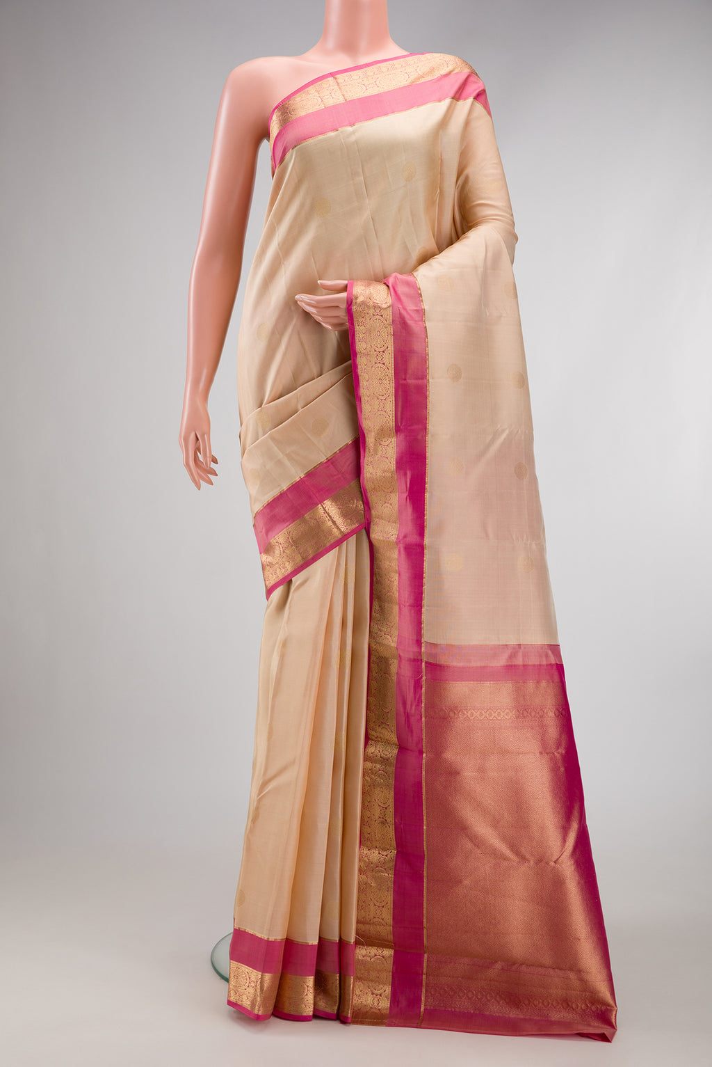 Beige Kanchipuram Silk Saree with Zari Butta on the body and Zari Border.  displayed on a mannequin