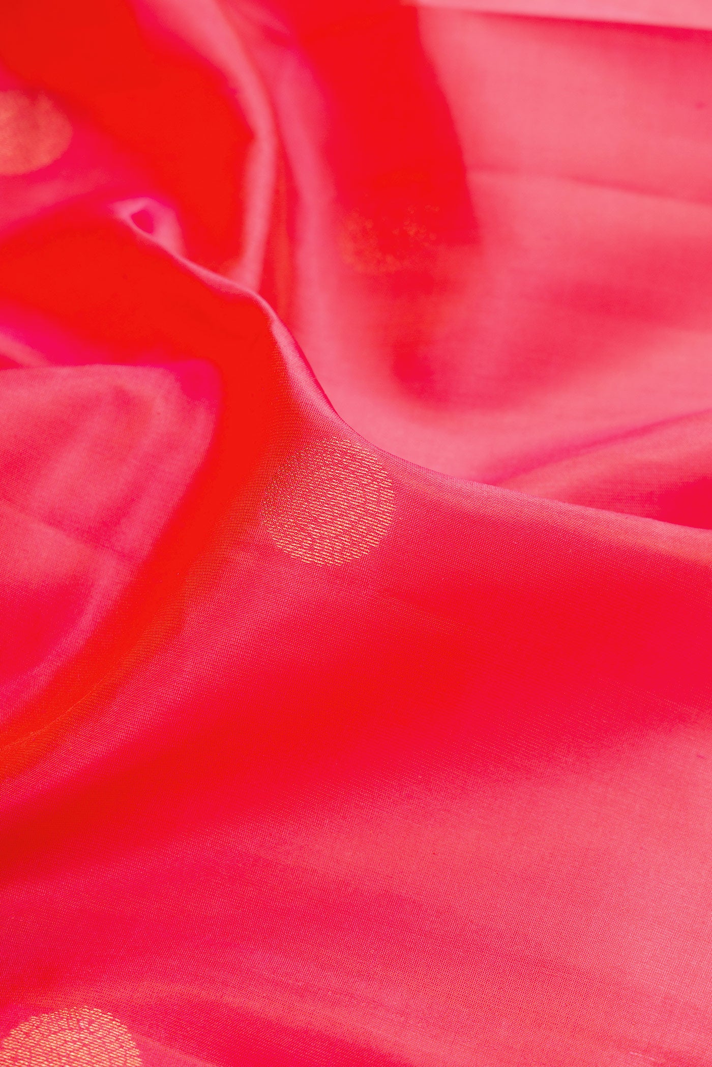 Close up of Coral Dual Tone Kanchipuram Silk Saree with Zari Butta on the body and Zari Border.  displaying folds