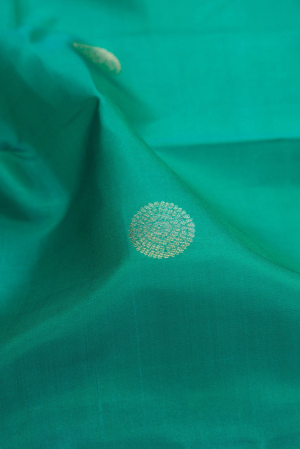 Close up of Green Kanchipuram Silk Saree with Zari Butta on the body and Zari Border.  displaying folds