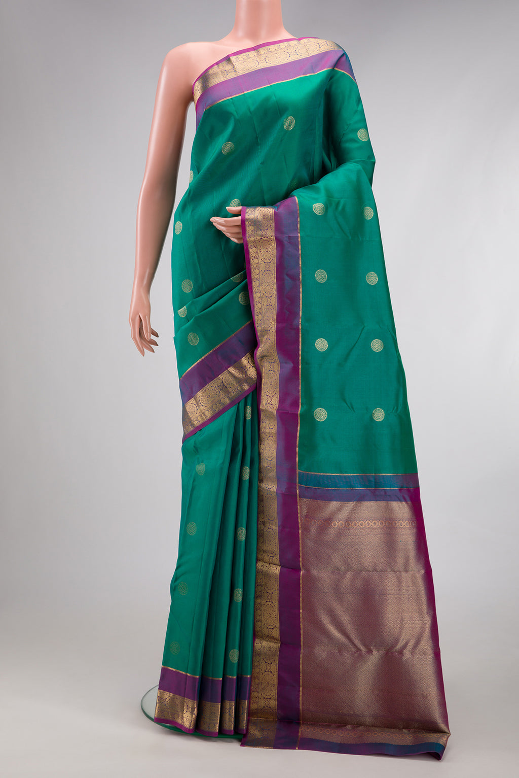 Green Kanchipuram Silk Saree with Zari Butta on the body and Zari Border.  displayed on a mannequin