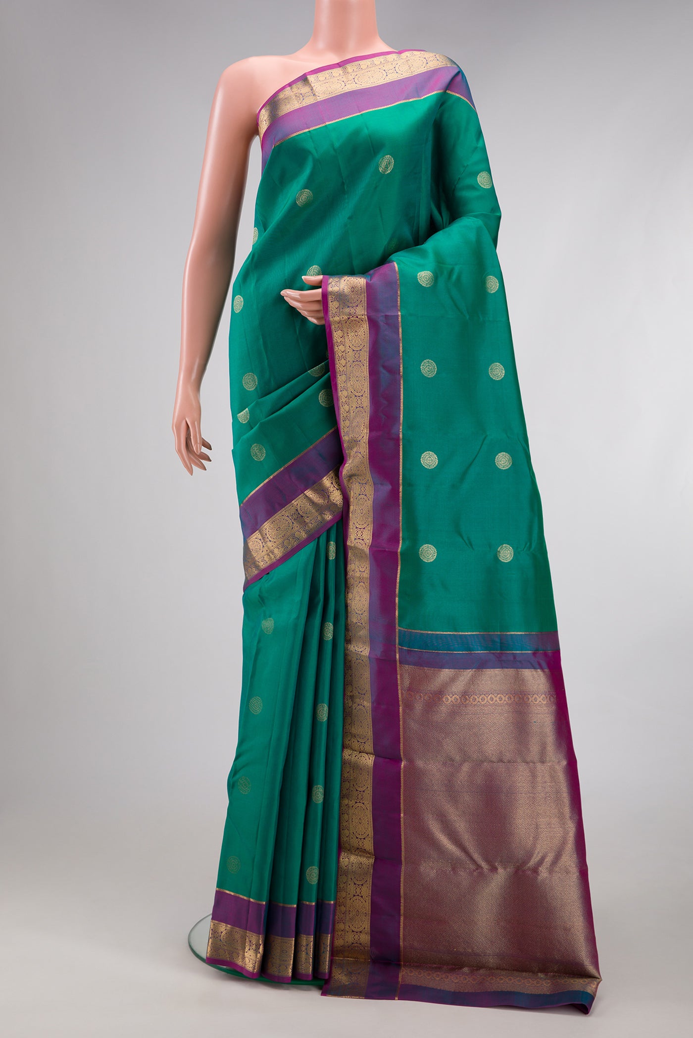 Green Kanchipuram Silk Saree with Zari Butta on the body and Zari Border.  displayed on a mannequin