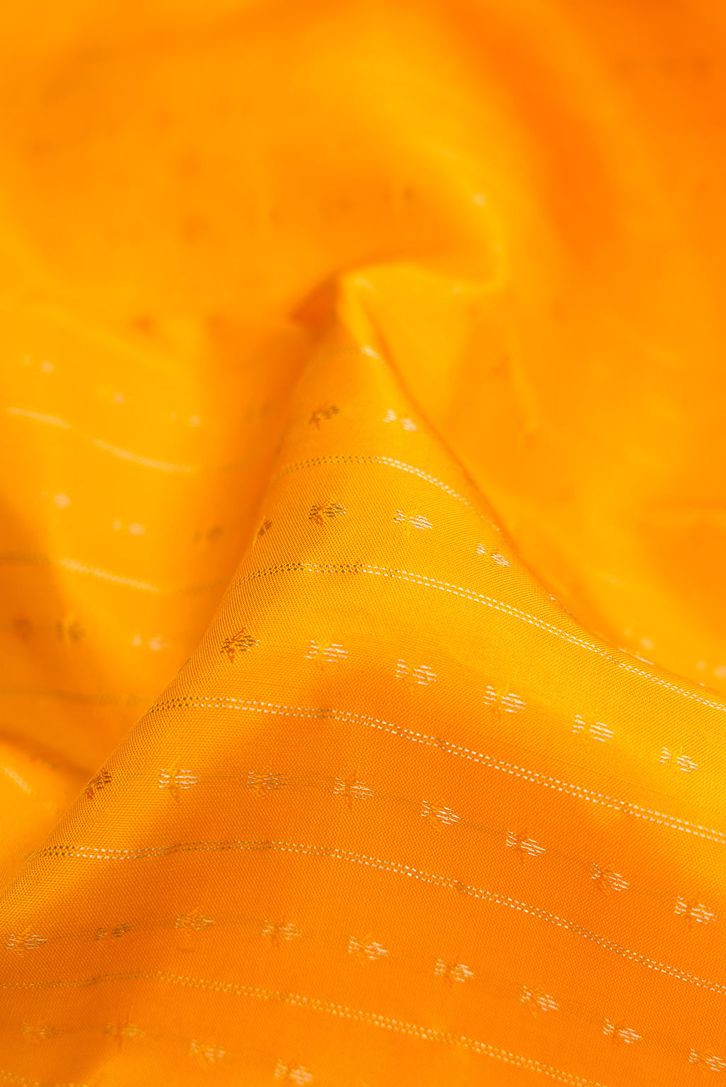 Close up of Yellow Dual Tone Kanchipuram Silk Saree with Zari Butta on the body and Zari Border.  displaying folds