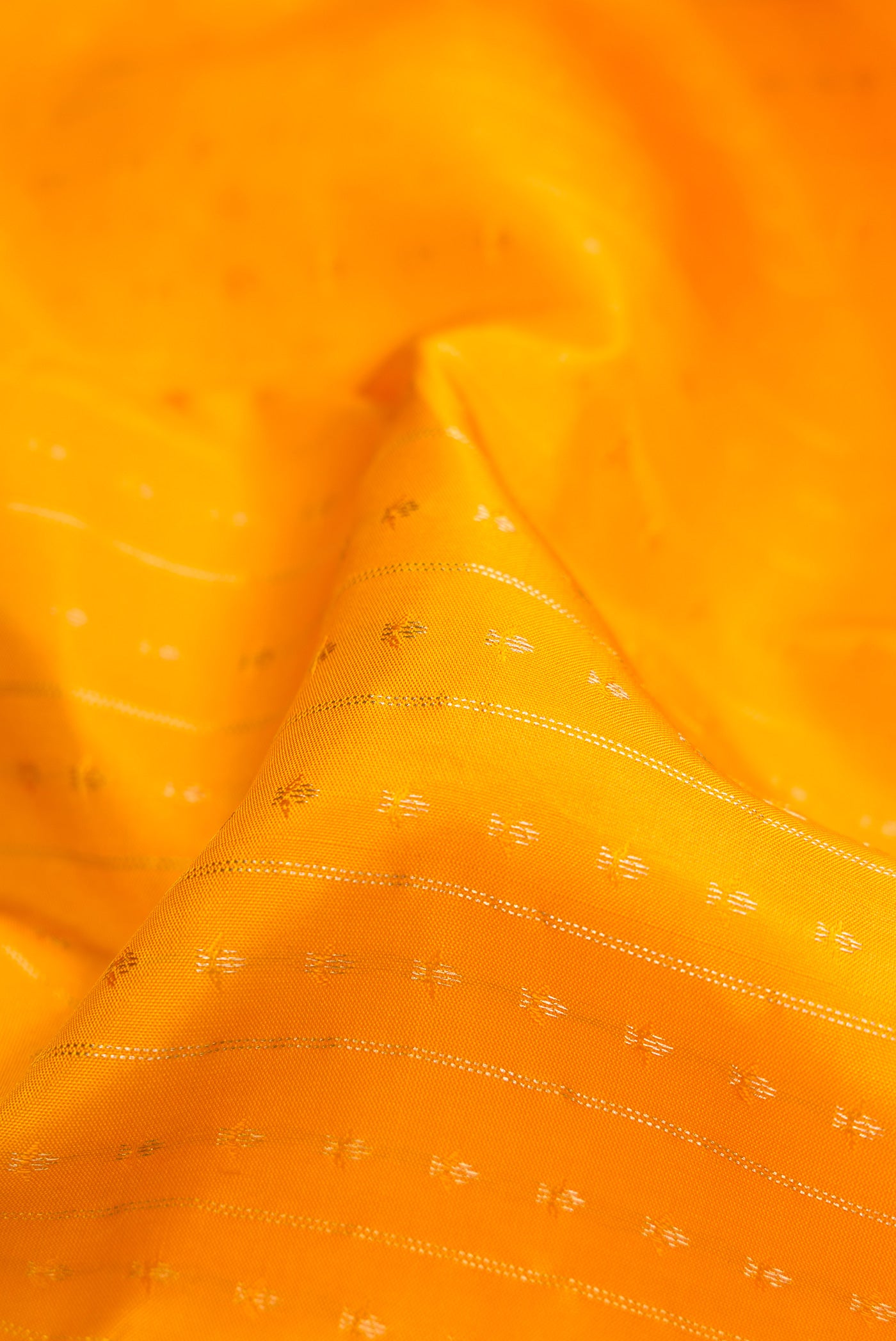 Close up of Yellow Dual Tone Kanchipuram Silk Saree with Zari Butta on the body and Zari Border.  displaying folds