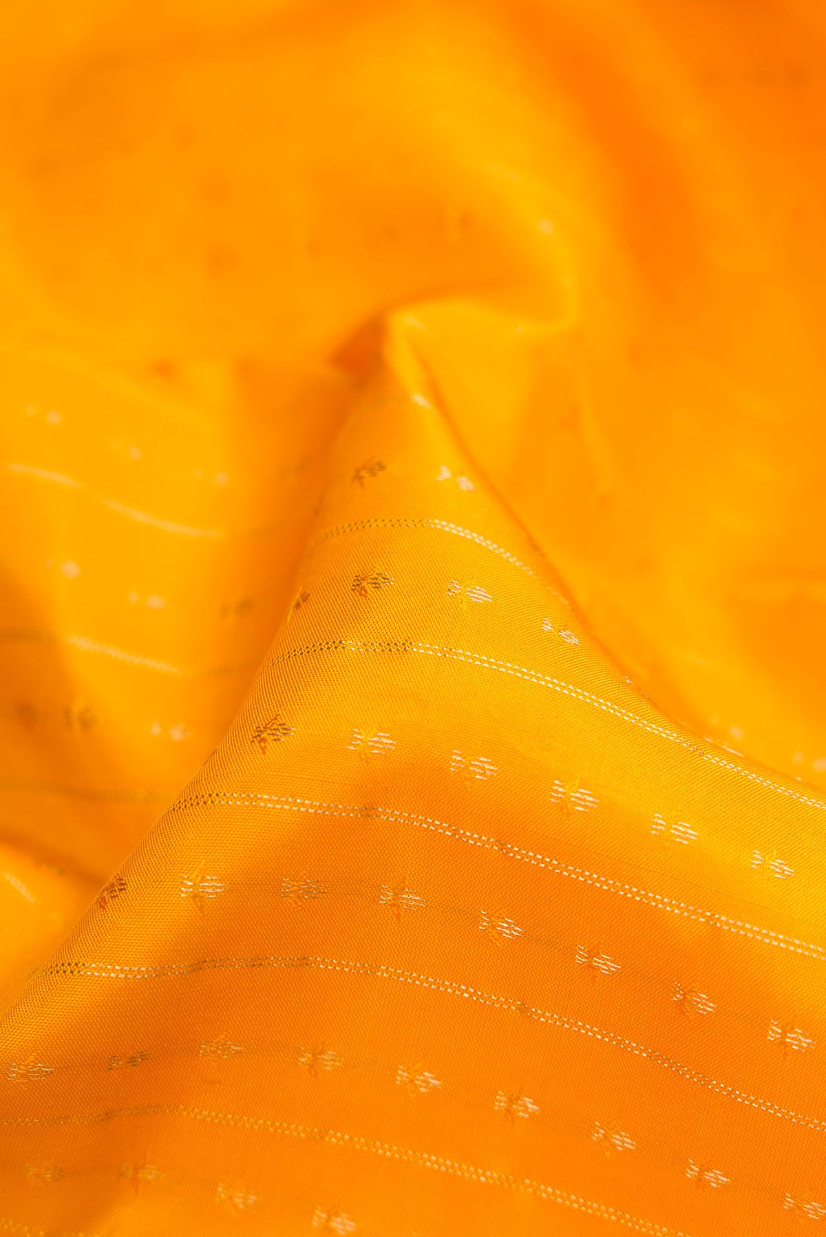 Close up of Yellow Dual Tone Kanchipuram Silk Saree with Zari Butta on the body and Zari Border.  displaying folds