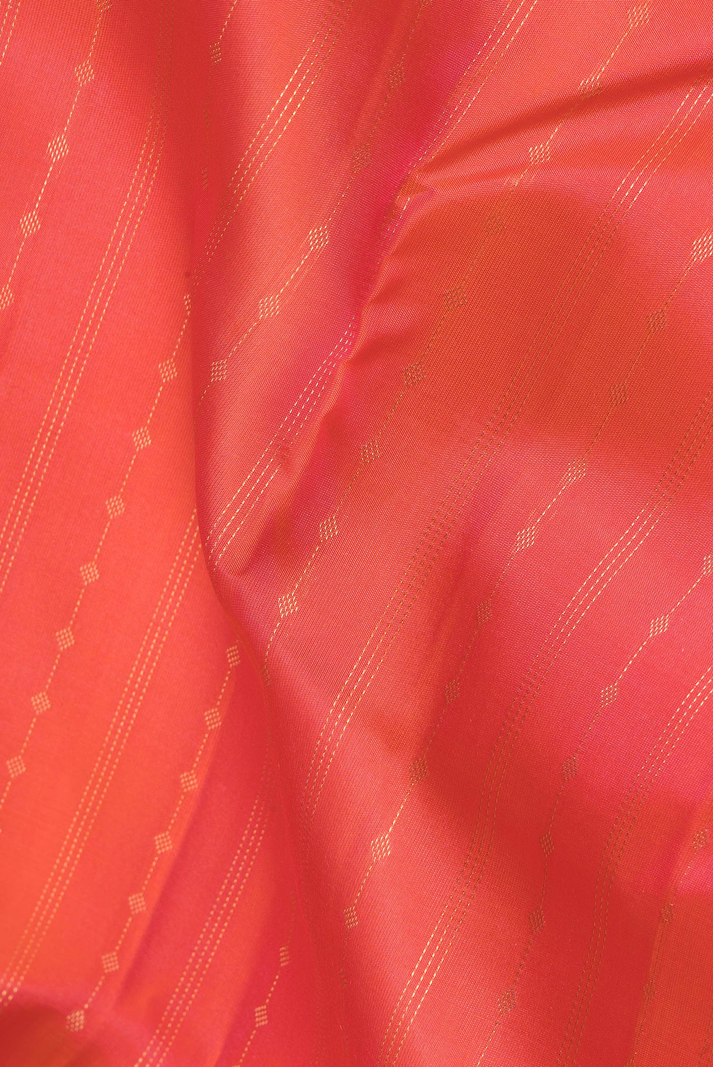 Close up of Brick Orange Dual Tone Kanchipuram Silk Saree with Zari Butta on the body and Zari Border.  displaying folds
