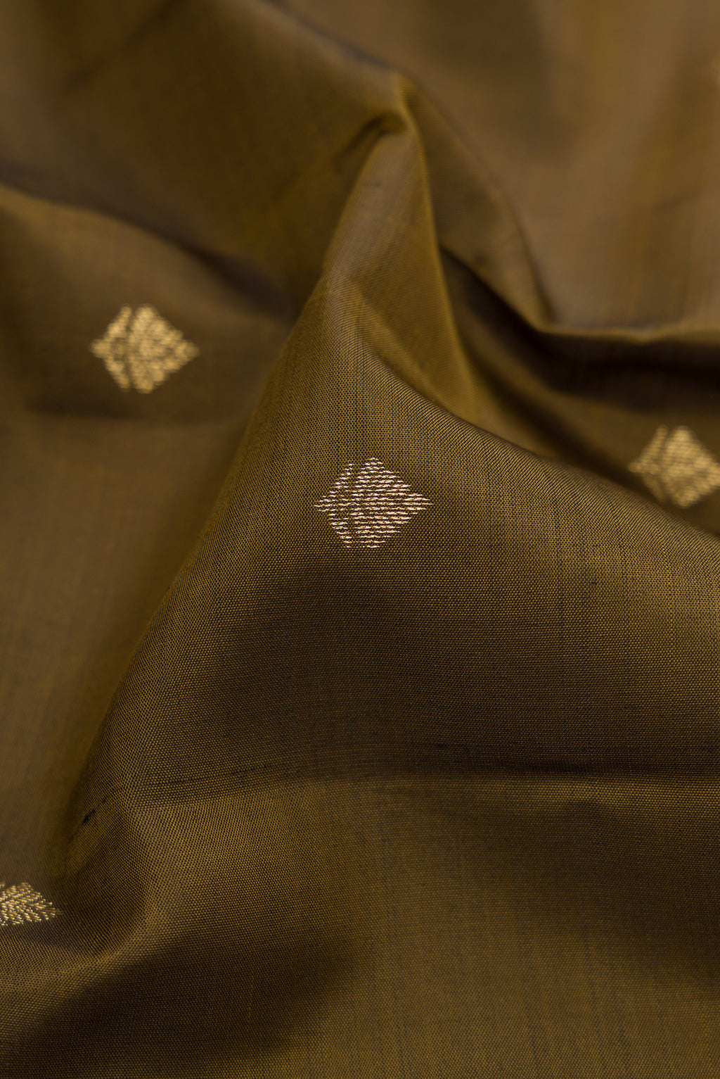 Close up of Mehandi Green Kanchipuram Silk Saree with Zari Butta on the body and Zari Border.  displaying folds