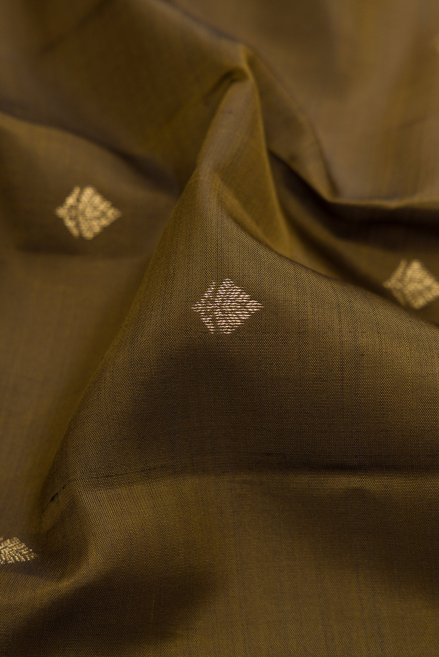 Close up of Mehandi Green Kanchipuram Silk Saree with Zari Butta on the body and Zari Border.  displaying folds