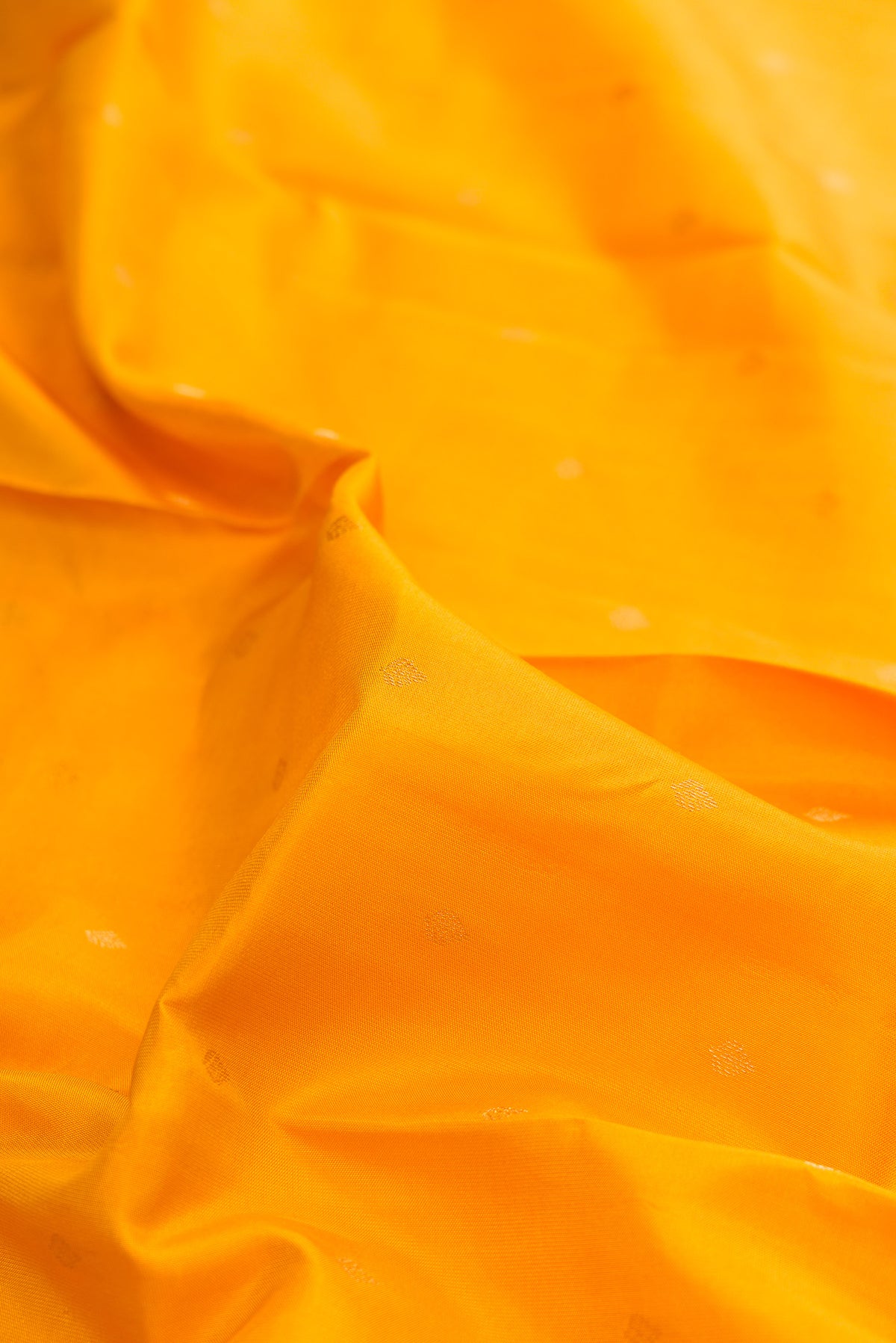 Close up of Pure Silk Yellow Kanchipuram Saree with Zari Butta on the body and Zari Border.  displaying folds