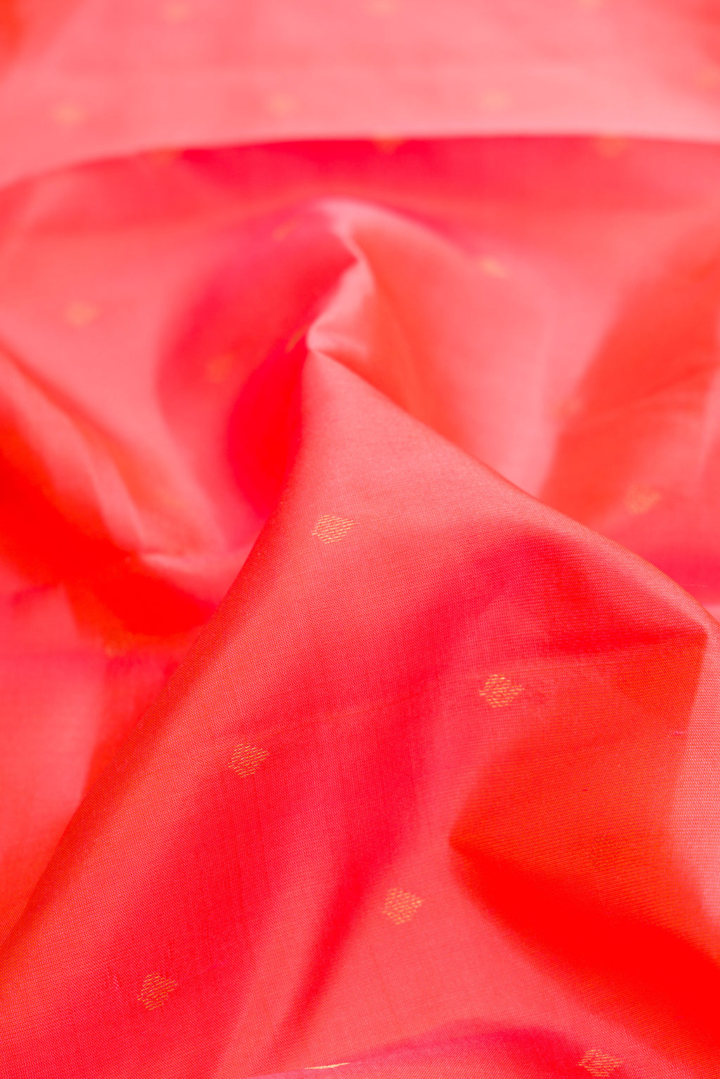 Close up of Coral Kanchipuram Silk Saree with Zari Butta on the body and Zari Border.  displaying folds