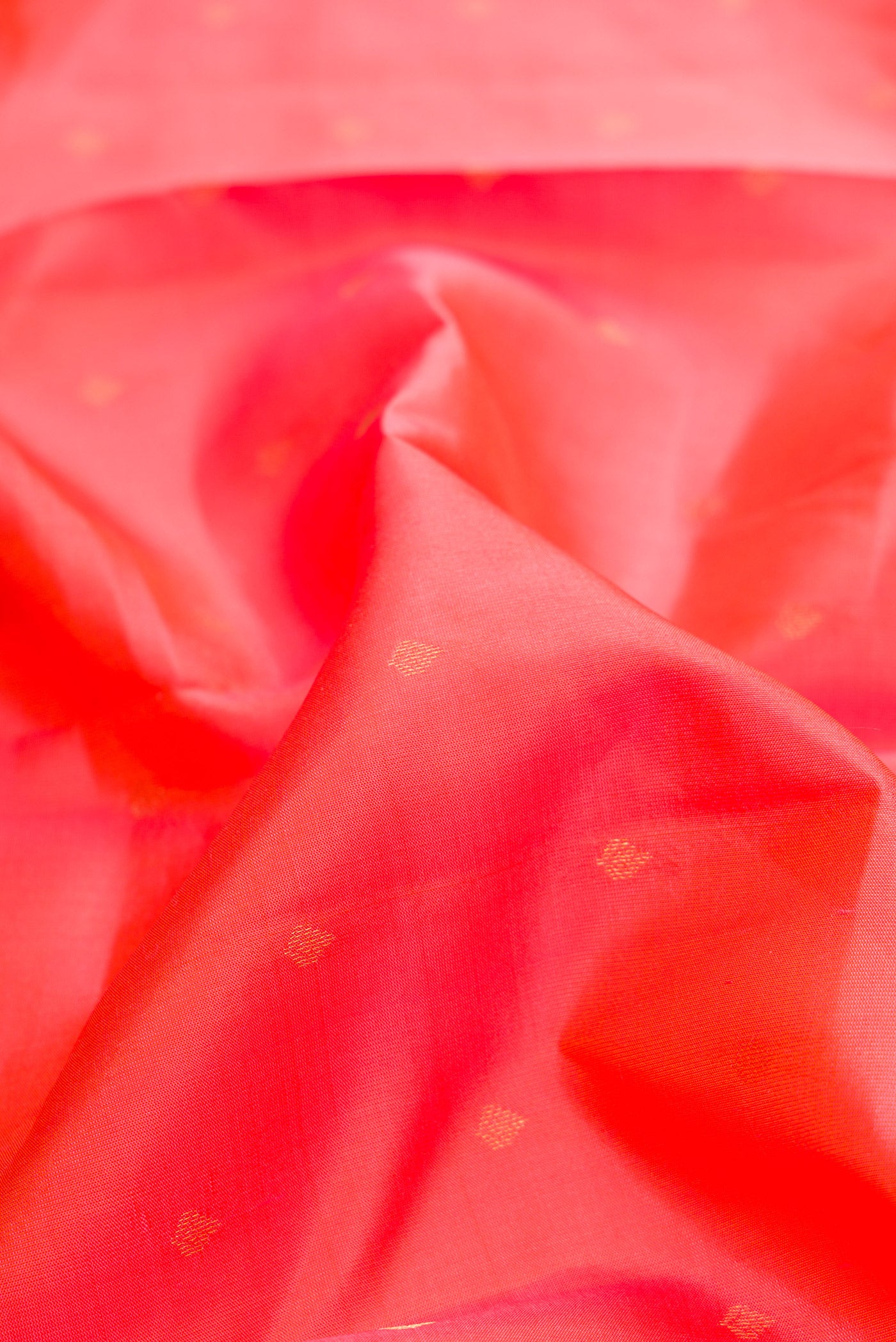 Close up of Coral Kanchipuram Silk Saree with Zari Butta on the body and Zari Border.  displaying folds