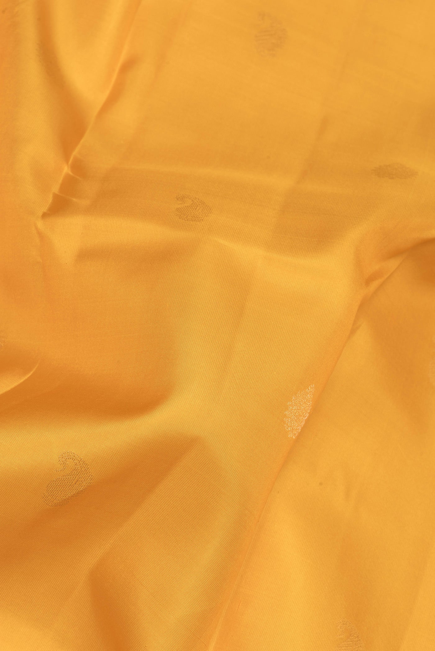 Close up of Yellow Kanchipuram Silk Saree with Zari Butta on the body and Zari Border.  displaying folds