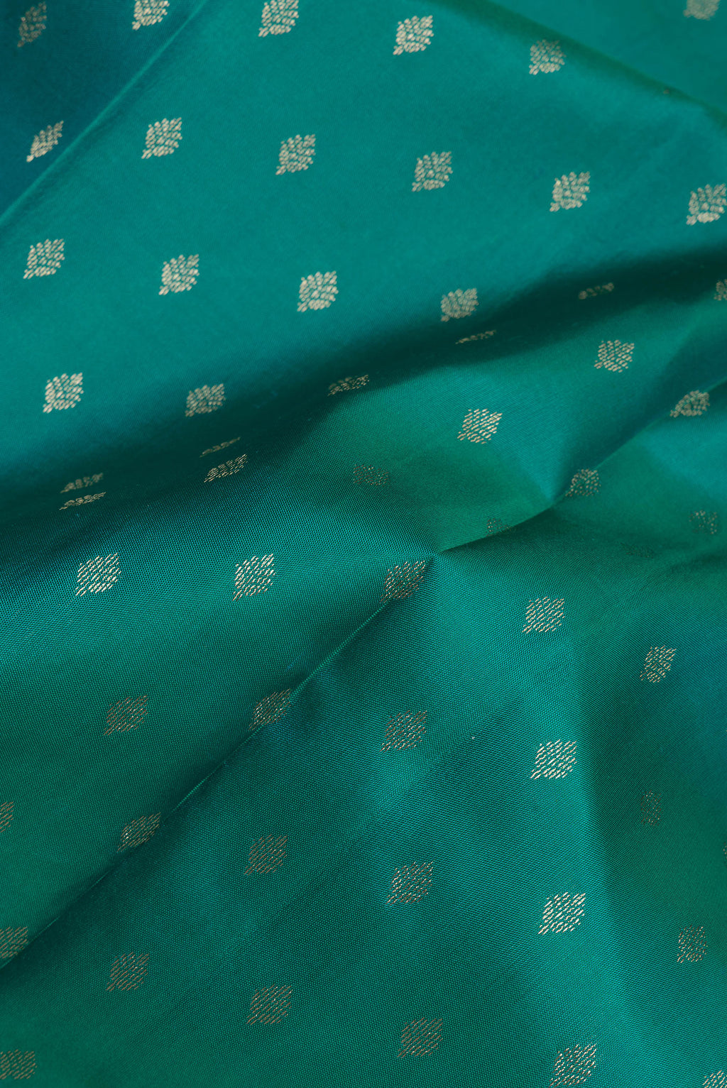 Close up of Green Kanchipuram Silk Saree with Zari Butta on the body and Zari Border.  displaying folds