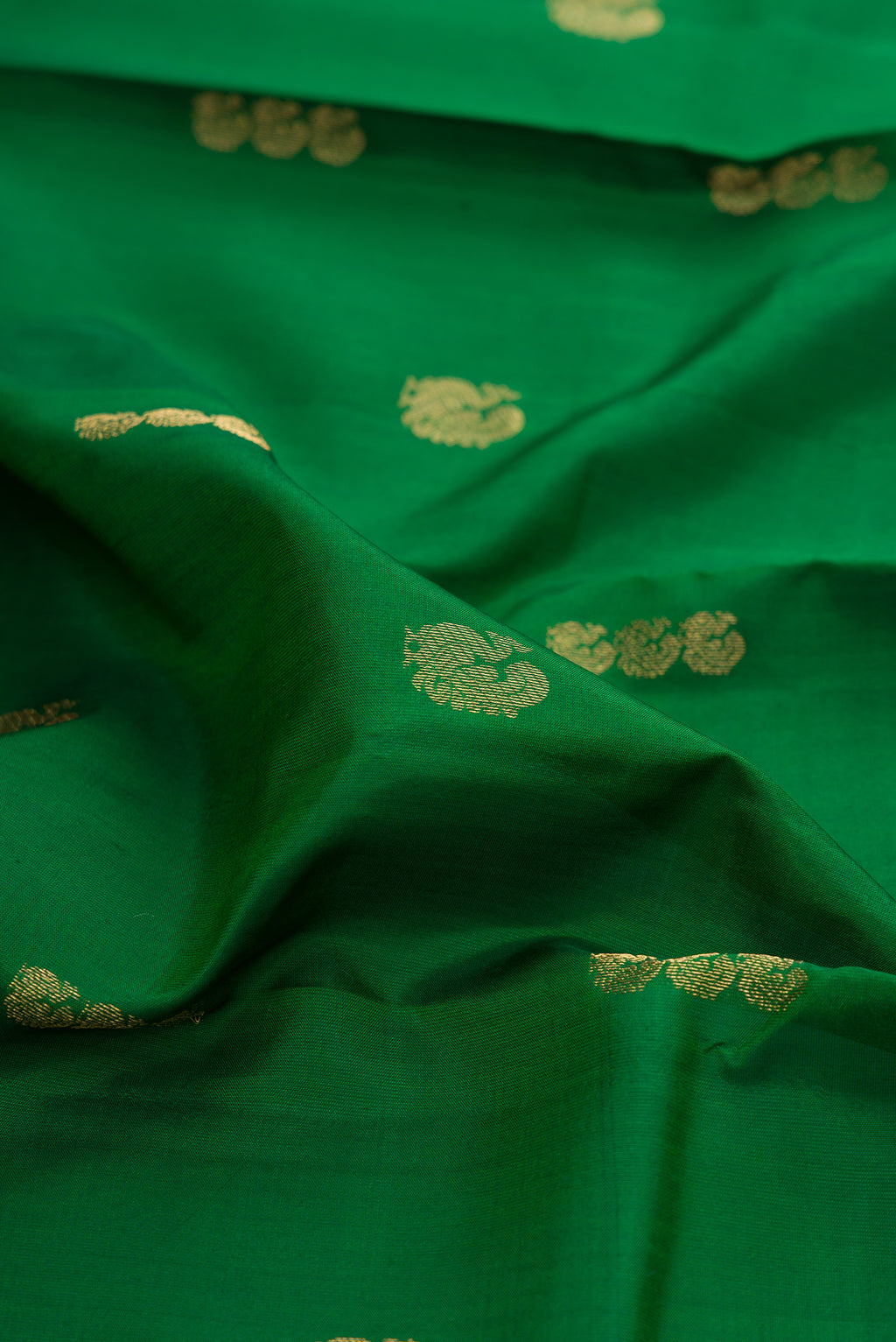 Close up of Green Kanchipuram Silk Saree with Zari Butta on the body and Zari Border.  displaying folds