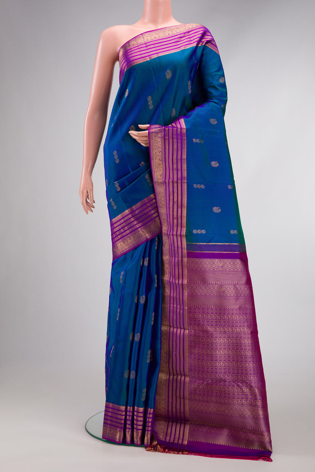 Peacock Blue Dual Tone Kanchipuram Silk Saree with Zari Butta on the body and Zari Border.  displayed on a mannequin