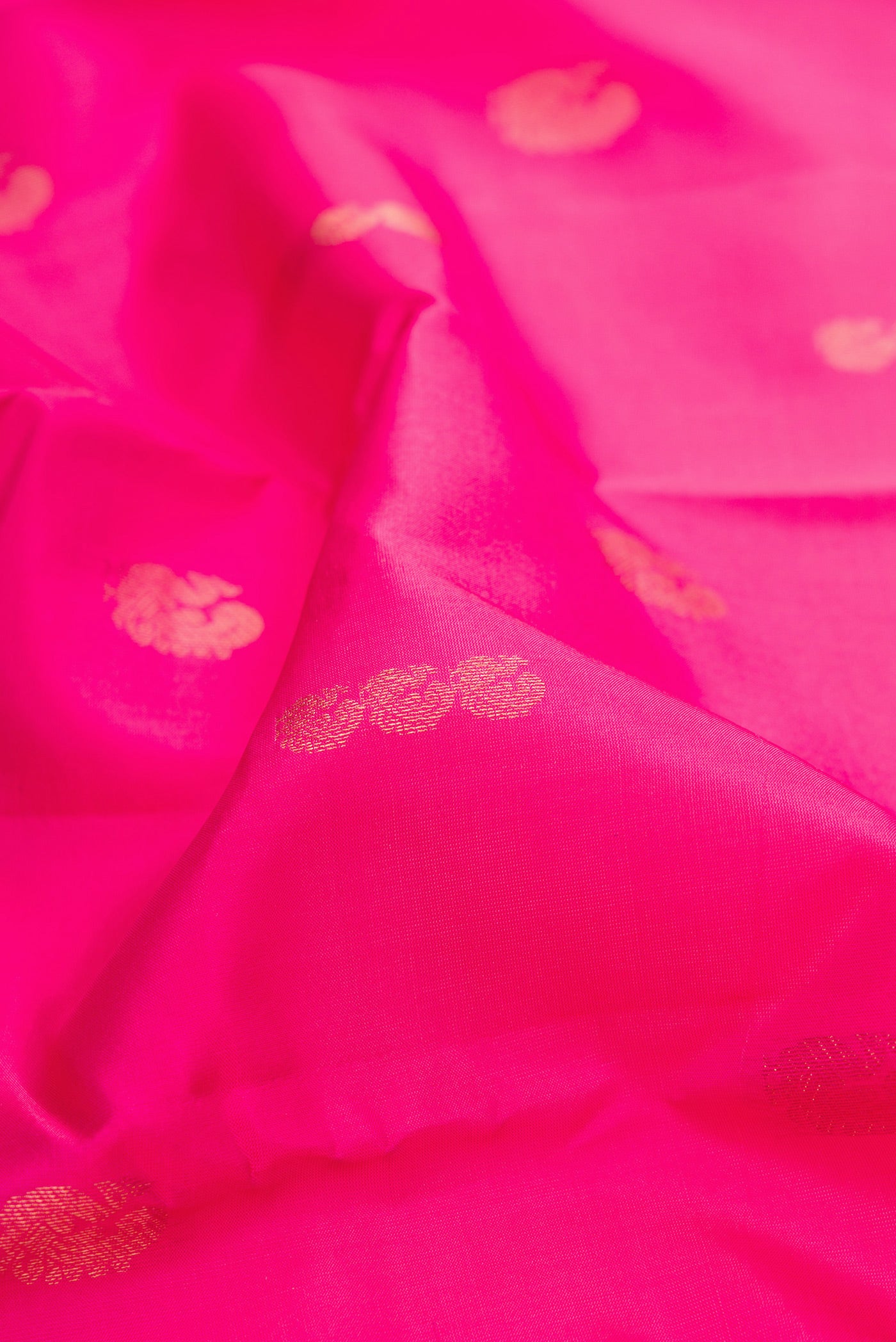 Close up of Pink Kanchipuram Silk Saree with Zari Butta on the body and Zari Border.  displaying folds