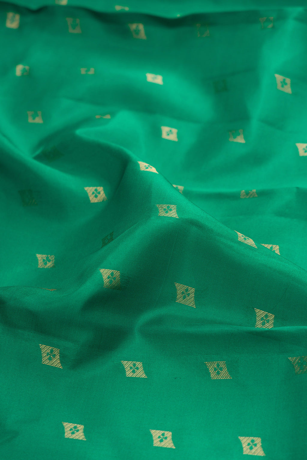 Close up of Green Kanchipuram Silk Saree with Zari Butta on the body and Zari Border.  displaying folds