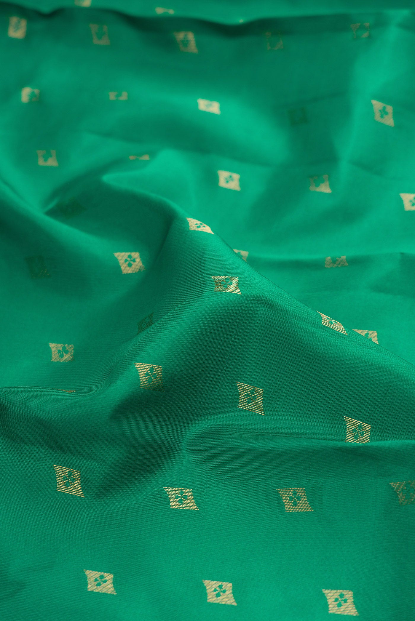 Close up of Green Kanchipuram Silk Saree with Zari Butta on the body and Zari Border.  displaying folds