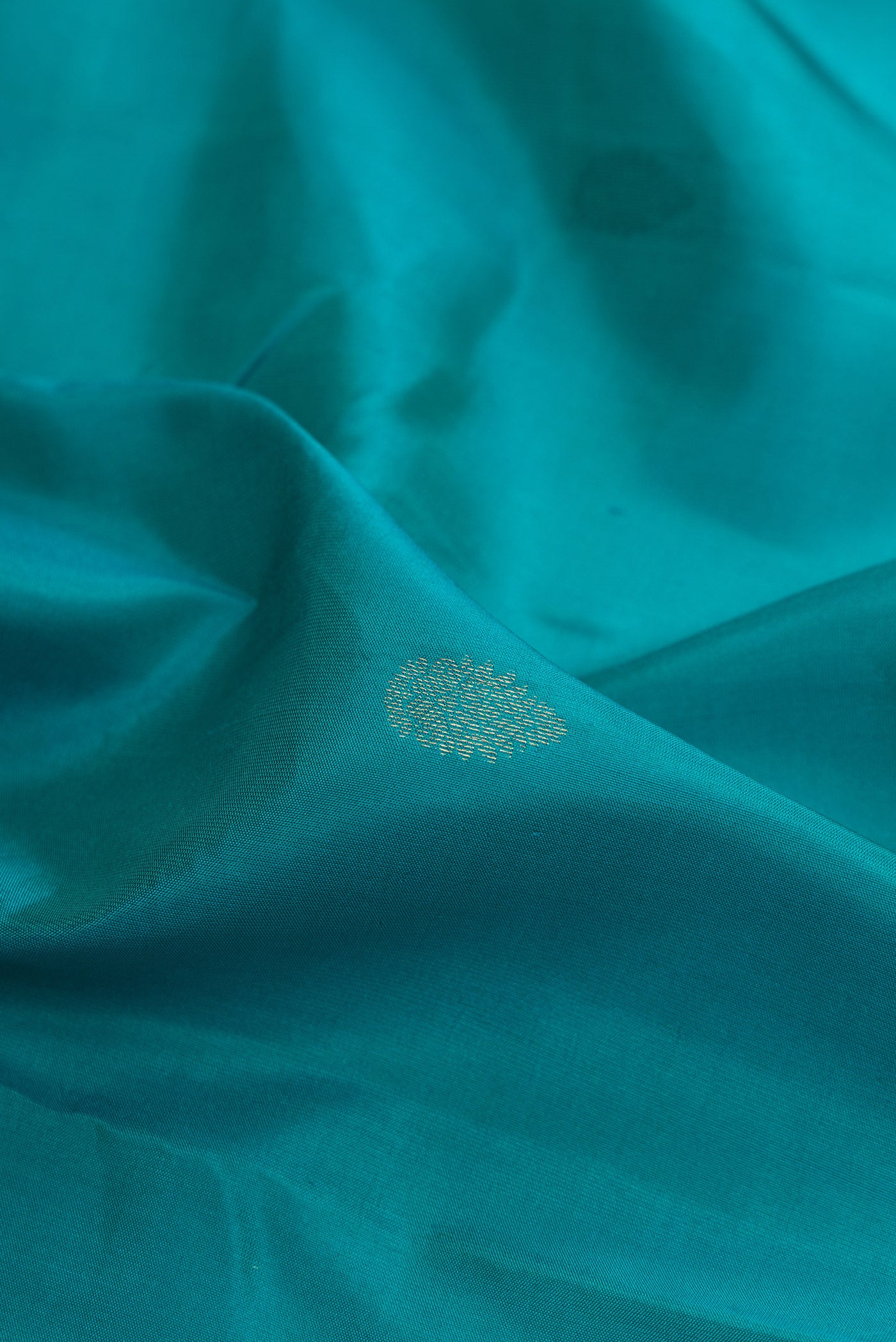 Close up of Teal Kanchipuram Silk Saree with Zari Butta on the body and Zari Border.  displaying folds