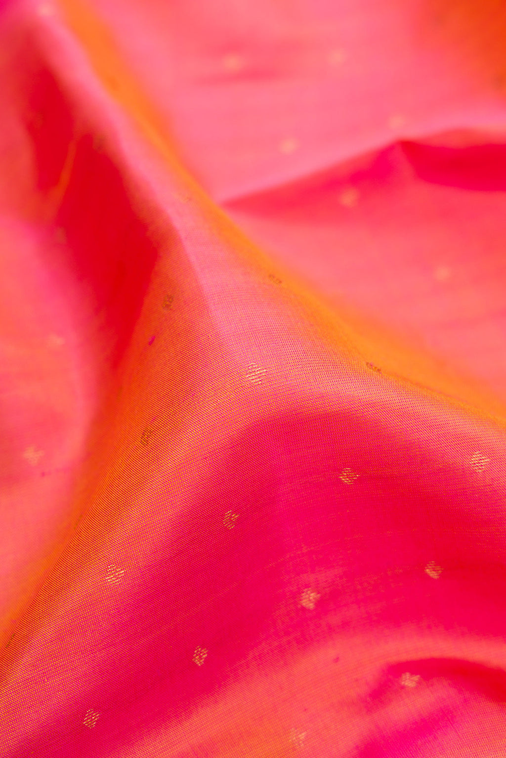 Close up of Pinkish Yellow Dual Tone Kanchipuram Silk Saree with Zari Butta on the body and Zari Border.  displaying folds