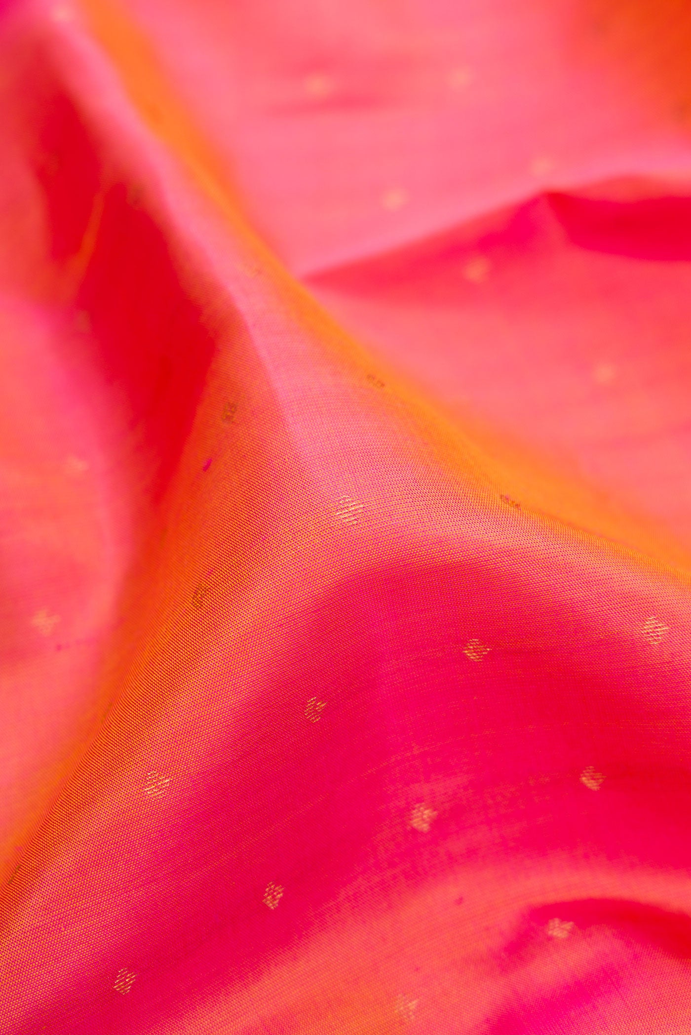 Close up of Pinkish Yellow Dual Tone Kanchipuram Silk Saree with Zari Butta on the body and Zari Border.  displaying folds