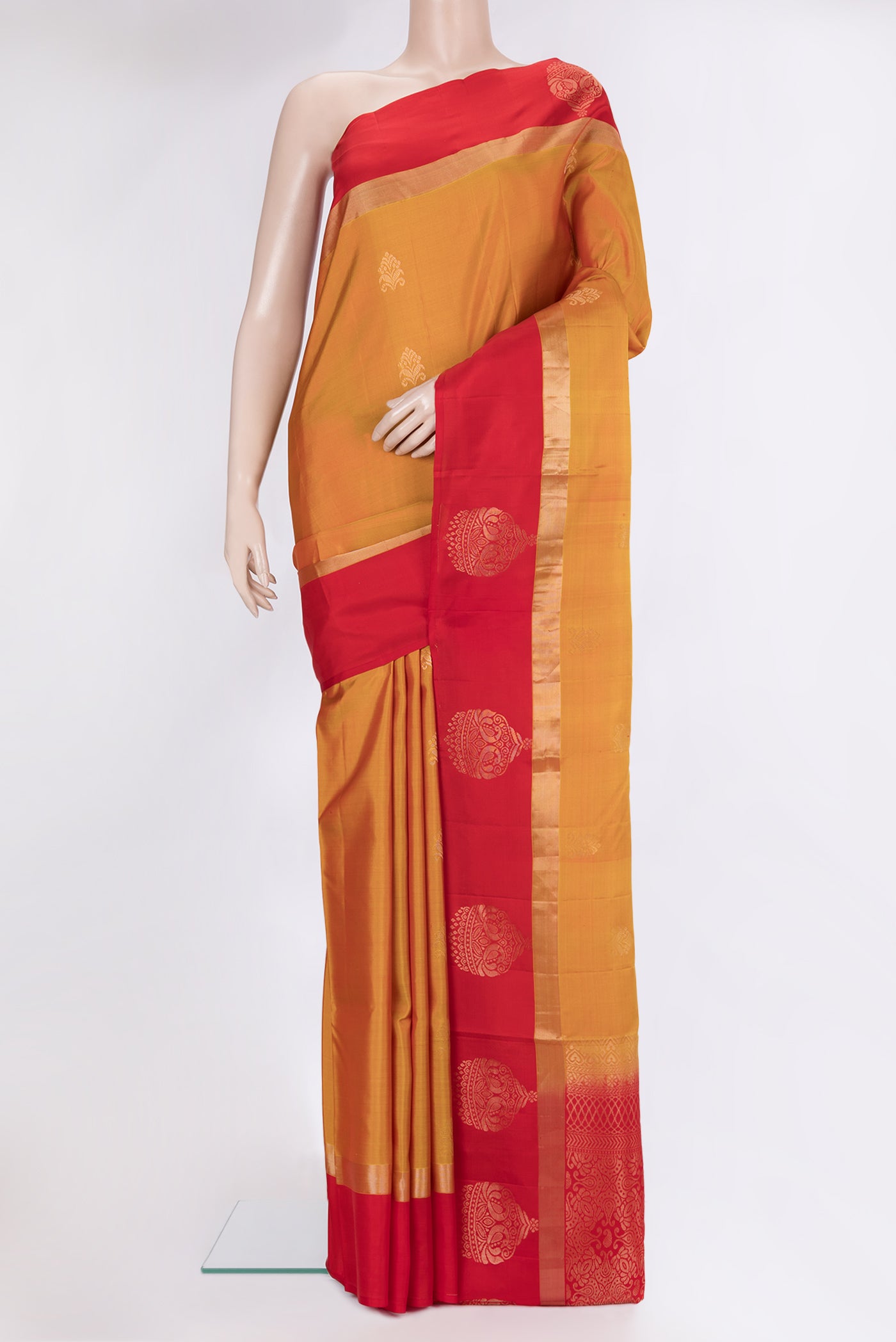 Mustard Soft Silk Saree with Zari Butta on the body and Fancy Border.  displayed on a mannequin