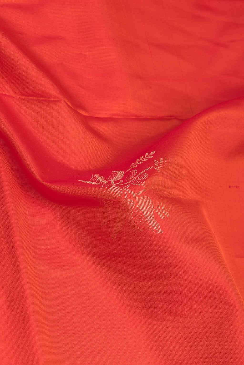 Close up of Orange Soft Silk Saree with Zari Butta on the body and Zari Border.  displaying folds