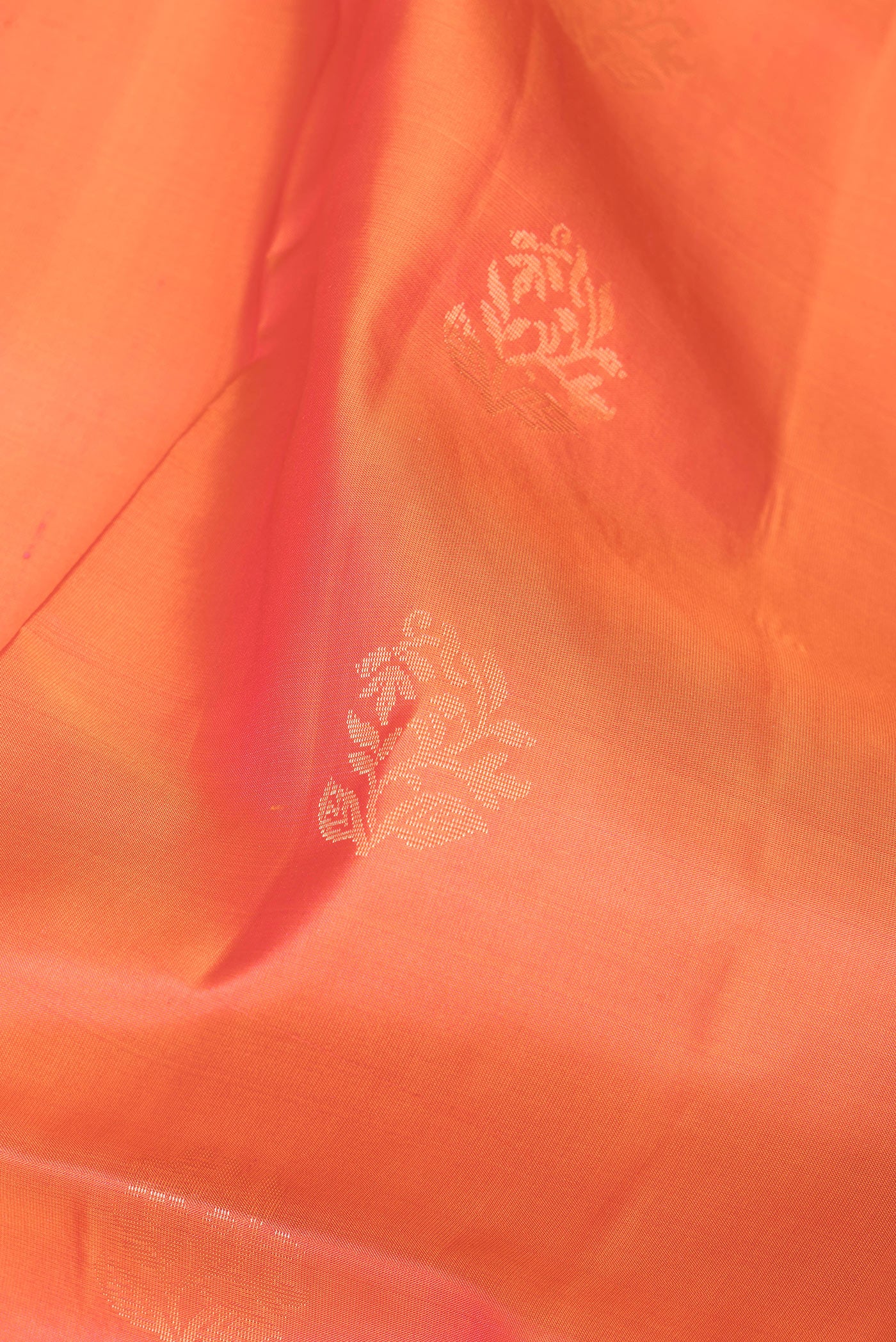 Close up of Orange Soft Silk Saree with Zari Butta on the body and Fancy Border.  displaying folds