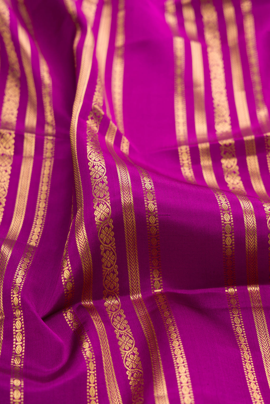 Close up of Magenta Kanjivaram Silk Saree with Stripes on the body and Zari Border.  displaying folds