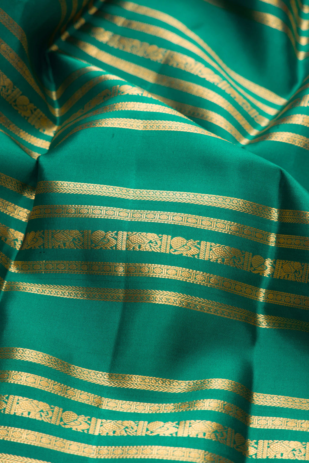 Close up of Green Kanjivaram Silk Saree with Stripes on the body and Zari Border.  displaying folds