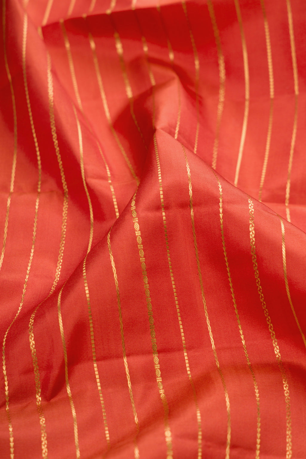 Close up of Brick Orange Kanjivaram Silk Saree with Stripes on the body and Zari Border.  displaying folds