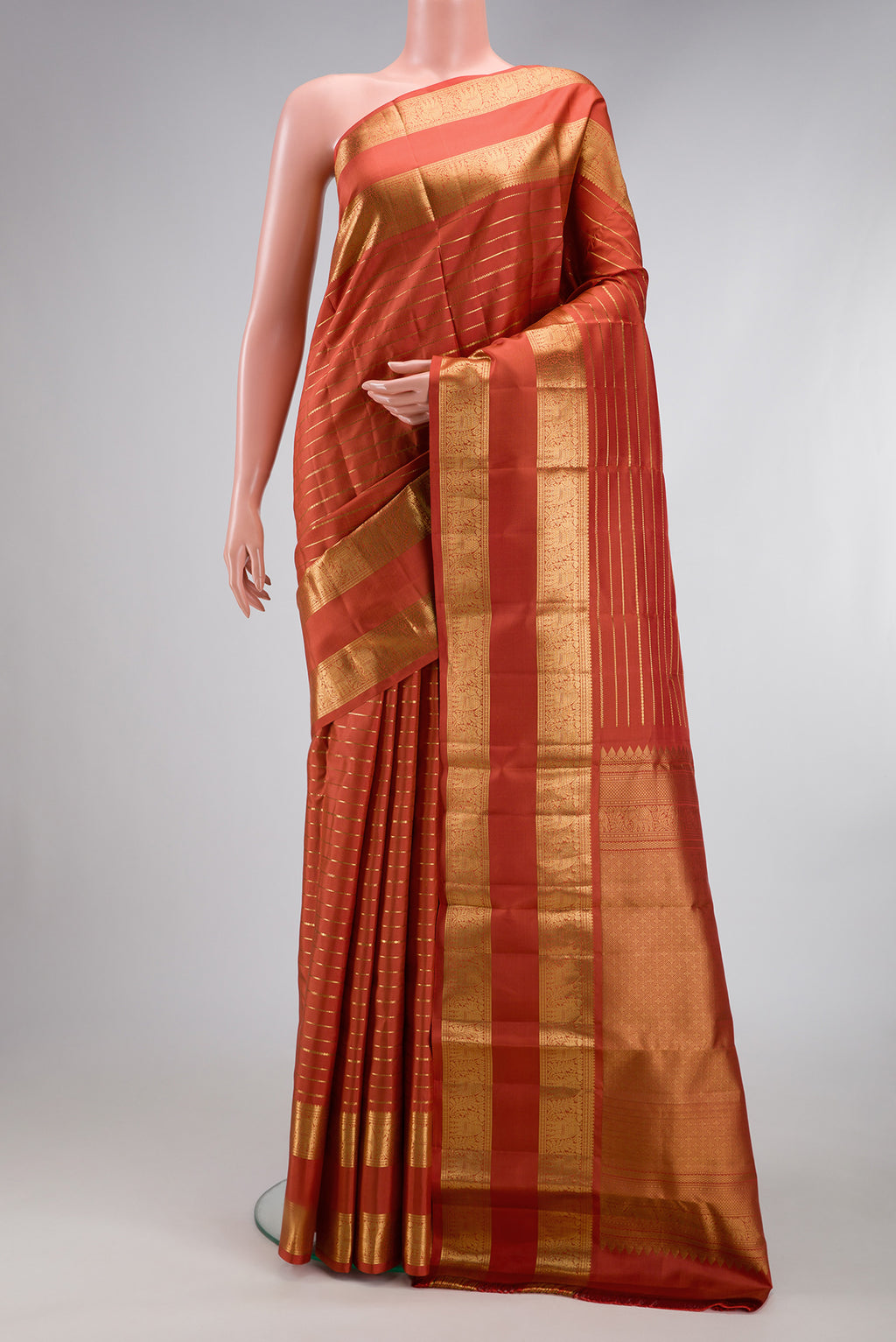Brick Orange Kanjivaram Silk Saree with Stripes on the body and Zari Border.  displayed on a mannequin