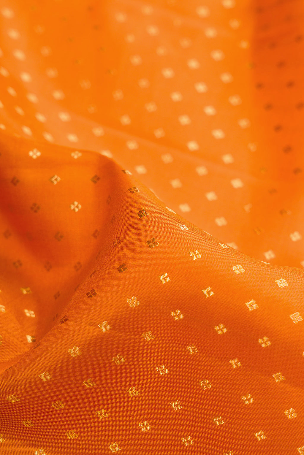 Close up of Orange Dual Tone Kanjivaram Silk Saree with Zari Butta on the body and Fancy Border.  displaying folds