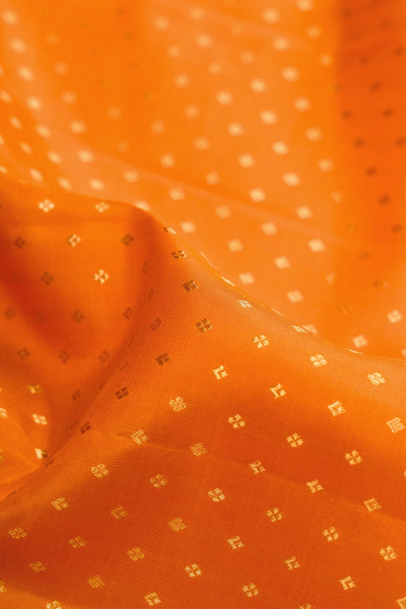 Close up of Orange Dual Tone Kanjivaram Silk Saree with Zari Butta on the body and Fancy Border.  displaying folds