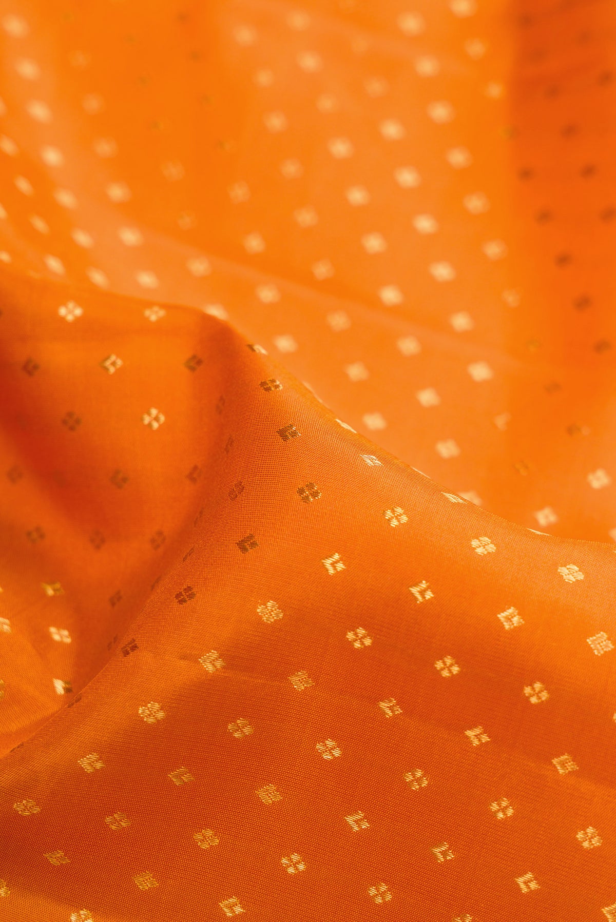 Close up of Orange Dual Tone Kanjivaram Silk Saree with Zari Butta on the body and Fancy Border.  displaying folds