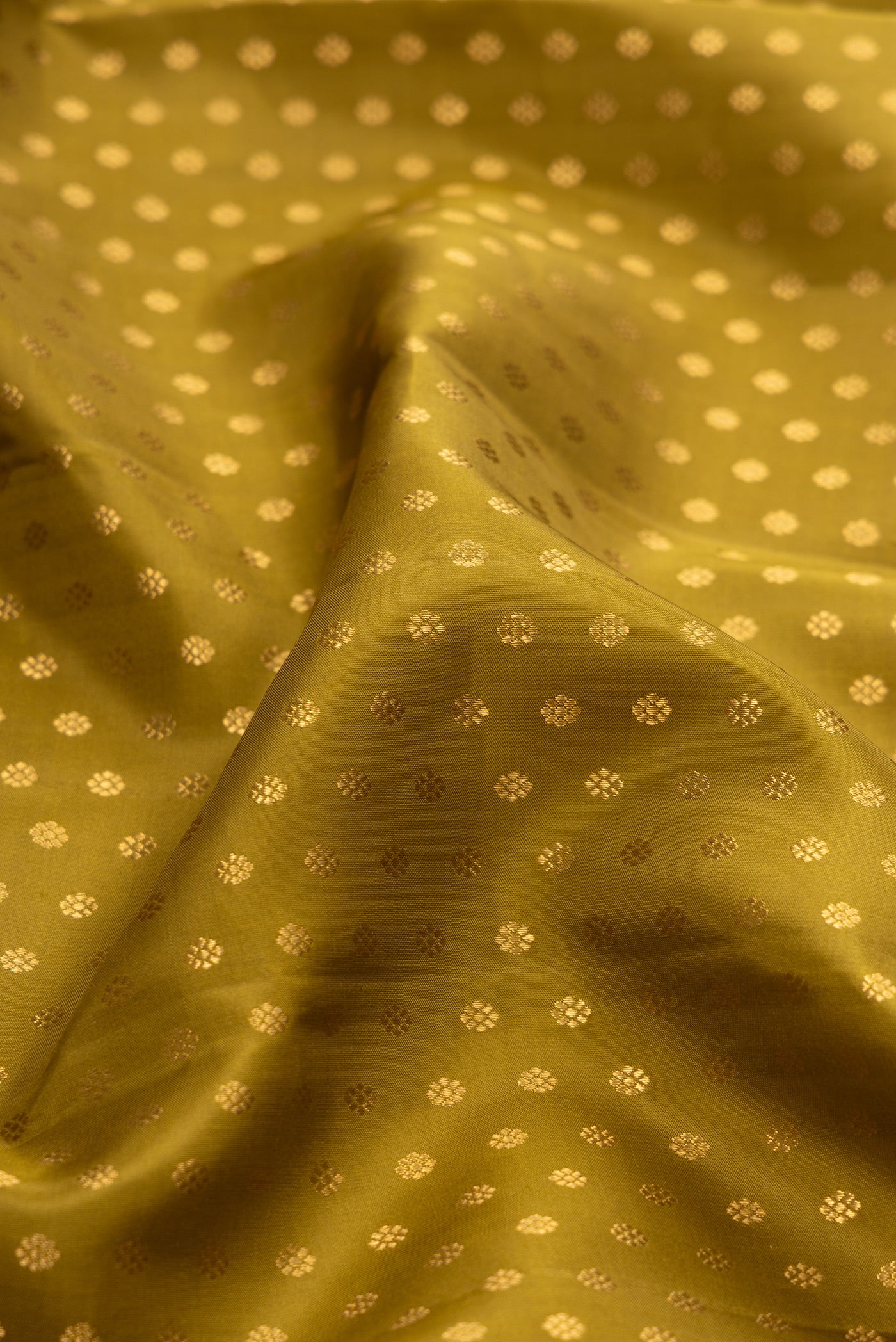 Close up of Mehandi Green Kanchipuram Silk Saree with Zari Butta on the body and Zari Border.  displaying folds